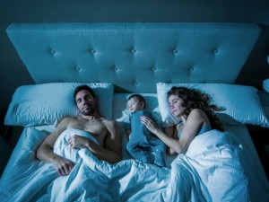 Một người mẹ và một người cha với đứa con của họ đang ngủ giữa họ