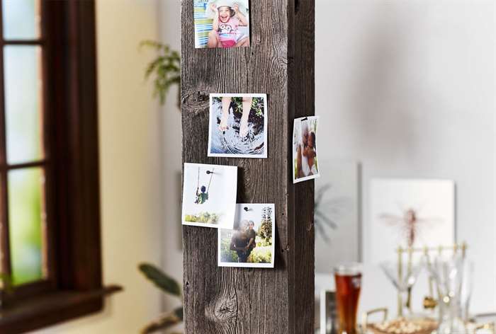 Square photo prints pinned on wooden post.