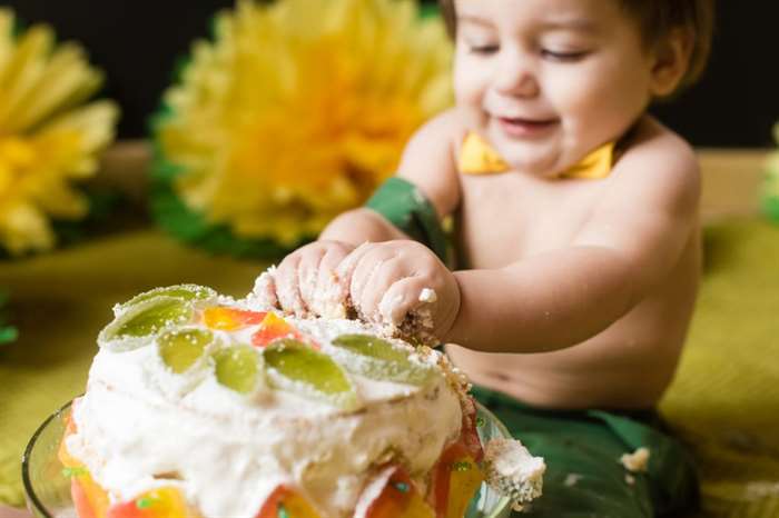 Happy boy destroys smash cake at his 3rd birthday. 