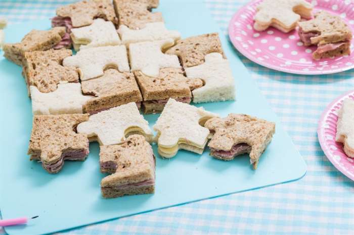 Birthday Party Food sandwich snack, jigsaw puzzle funny shape on table.