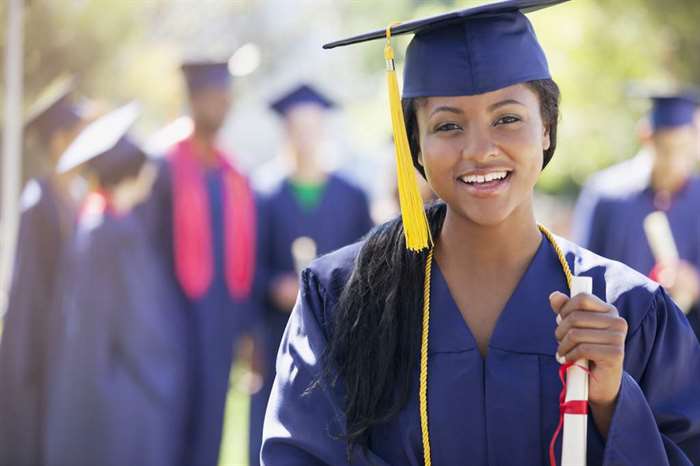 Smiling graduate holding diploma for school picture day.