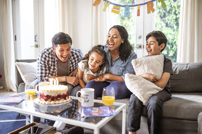 Happy family celebrating a birthday in the living room with cake