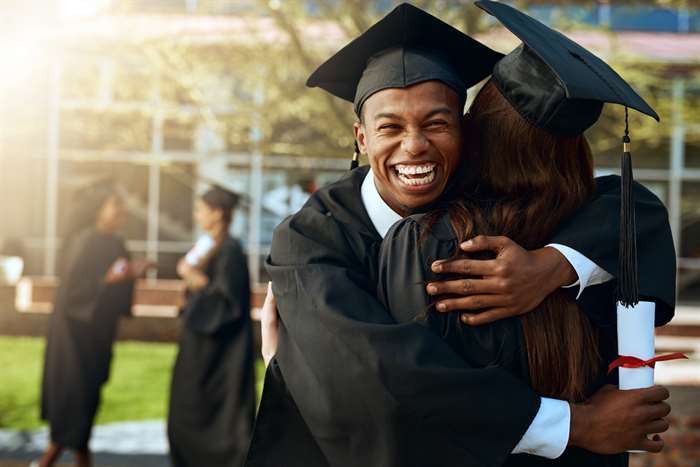 Portrait of a happy young man and woman hugging on graduation day