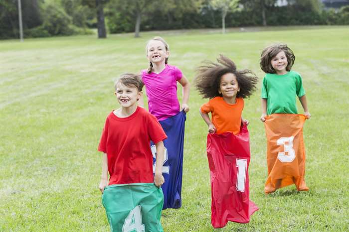 kids potato sack racing together at summer camp