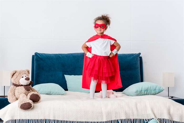 little girl playing dress up as a superhero at home