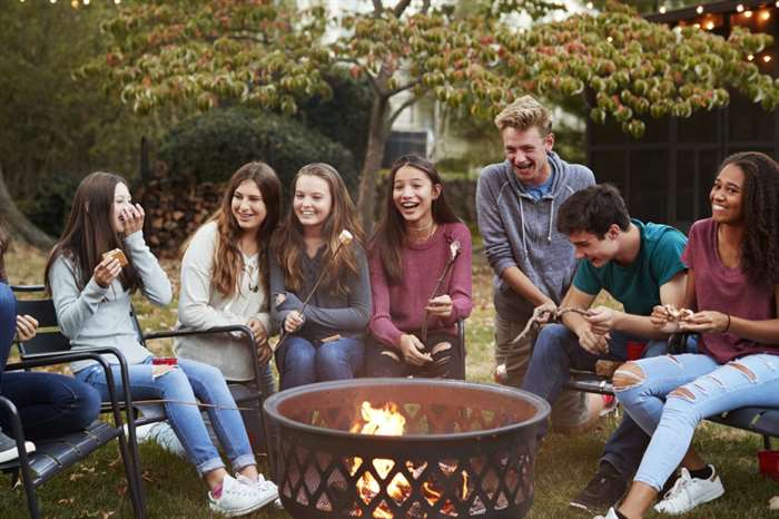 Những người bạn tuổi teen ngồi quanh hố lửa nướng kẹo dẻo.