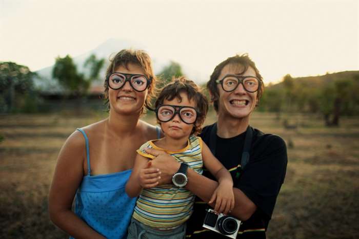 Parents and baby wear silly glasses for the camera.
