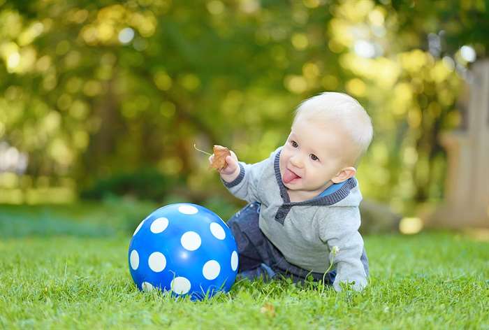 Em bé với quả bóng trên cỏ.