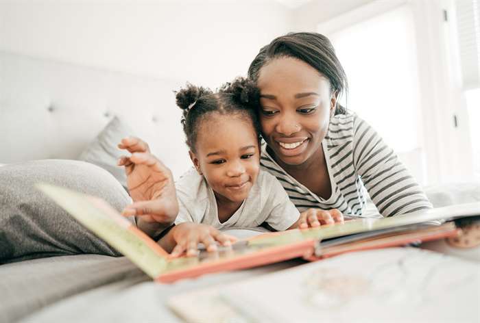 Mother and daughter reading story book.