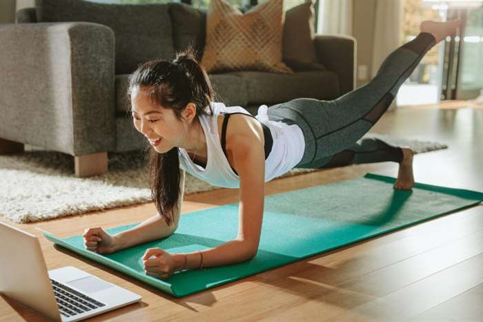 girl following an at home yoga class on laptop