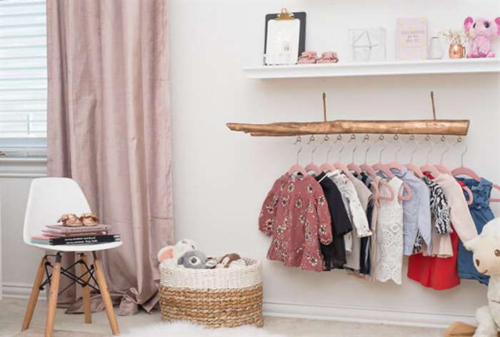 Baby girl clothes hanging on wooden rod.