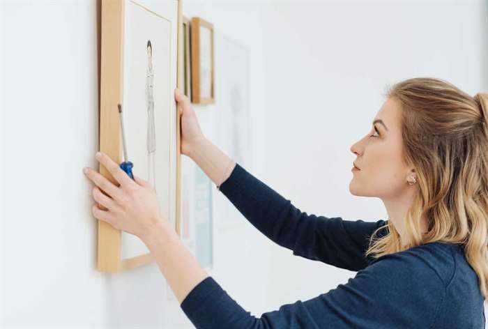 Woman hanging up a picture. 