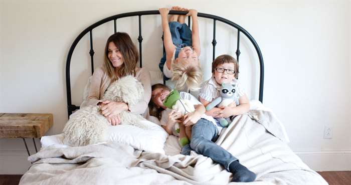 Mom with three kids in bed playing around