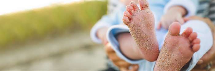 Chân em bé phủ đầy cát