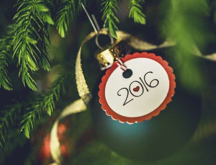 Christmas bauble with New Year message on Christmas tree branches.