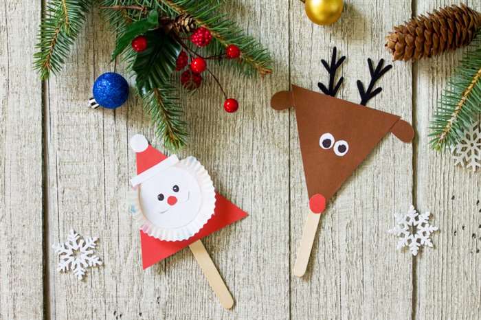 Santa and Reindeer stick Christmas craft on wooden table.