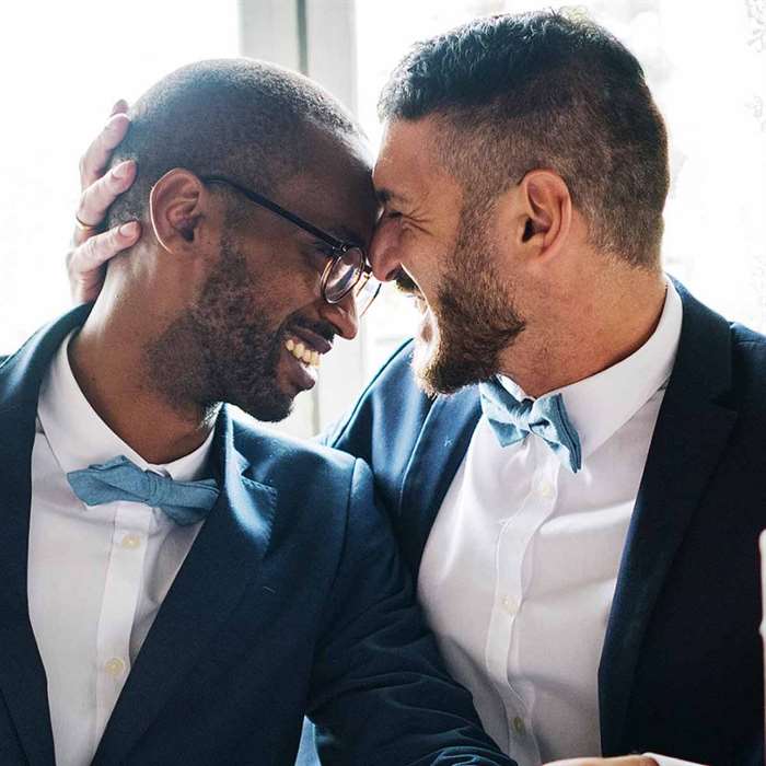 Two grooms smiling and laughing at wedding