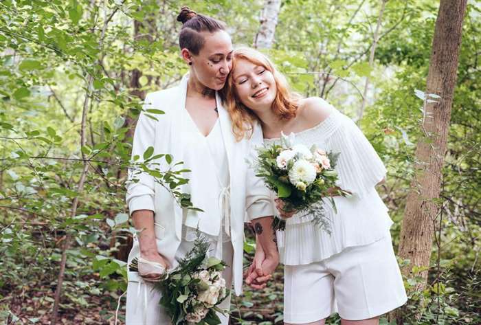 Two brides smiling at wedding in nature