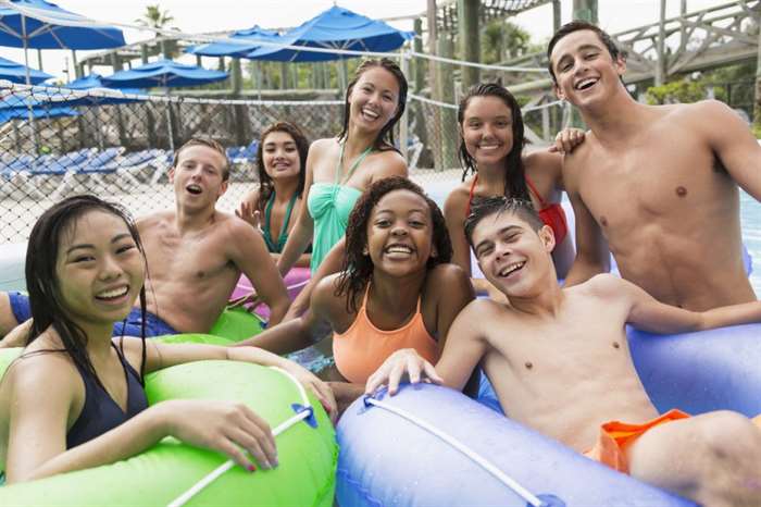 group of teens floating on inflatable rings at a water park.