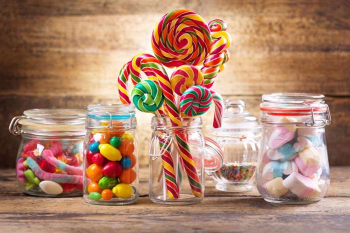 Colorful candies, jellies, lollipops, marshmallows and marmalade in a glass jars on wooden table