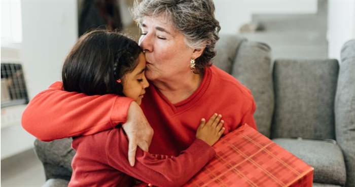 Grand daughter giving present to grand mother on christmas morning 