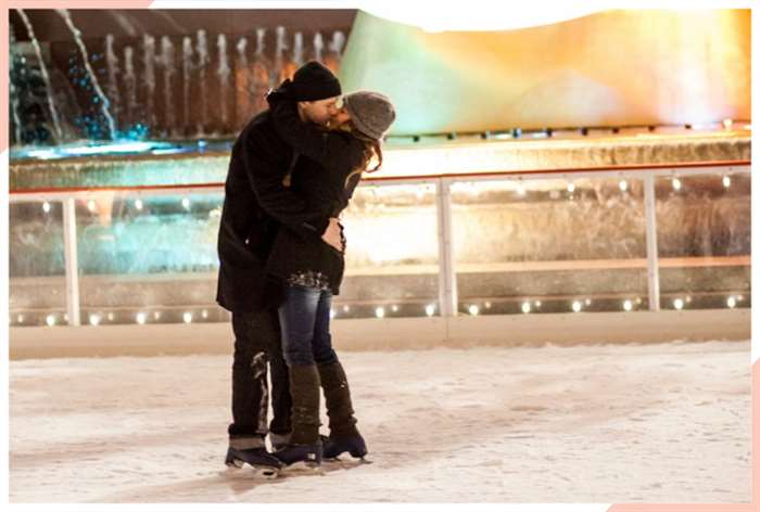 kiss by a fountain christmas engagement photo