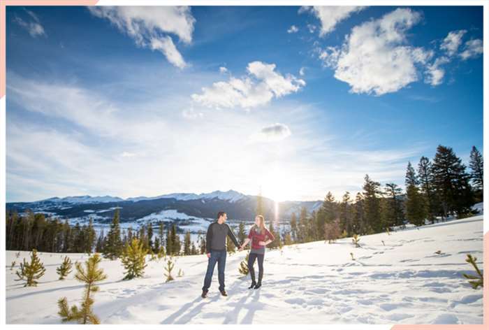 couple by snowy forest christmas engagement photo