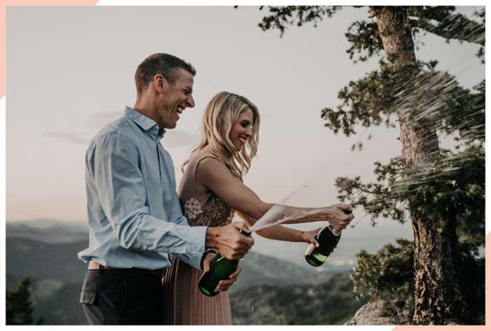 couple spraying champagne christmas engagement photo