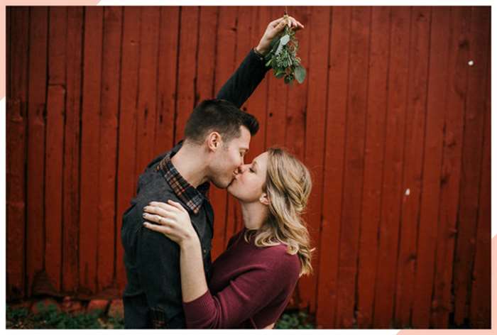 couple kiss under mistletoe christmas engagement photo