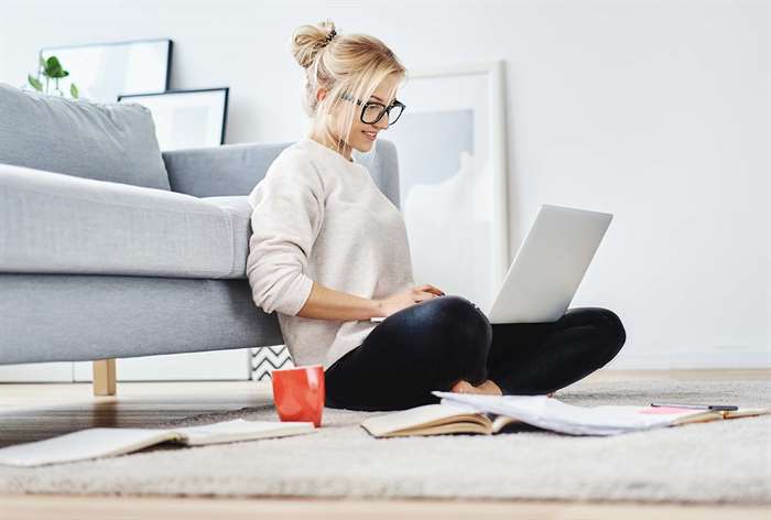 Woman sitting on the ground typing on a laptop