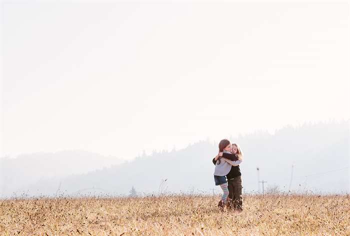 sibling photo ideas hugging in field