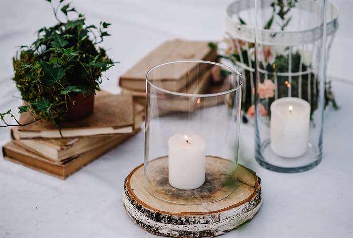 Old books next to candles in glass vases.