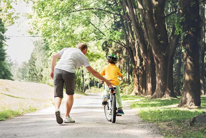 Dad helping son ride bike.