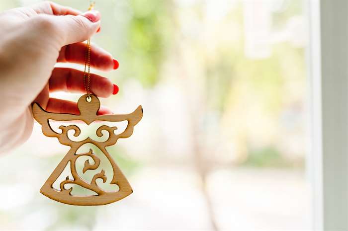 Christmas wooden decorations, angel in hand on light background. 