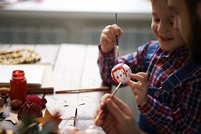 Boy showing self-painted Christmas ball to his Dad.