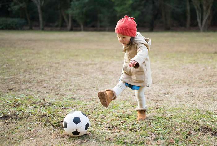 Toddler girl kicking soccer ball.