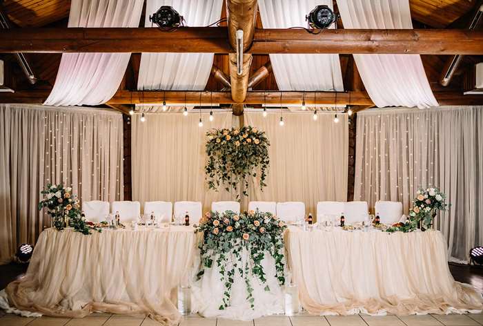 Wedding reception head table with white tablecloth and flowers.