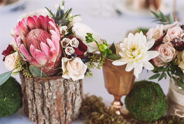 Wedding florals in small tree stump and copper cup.