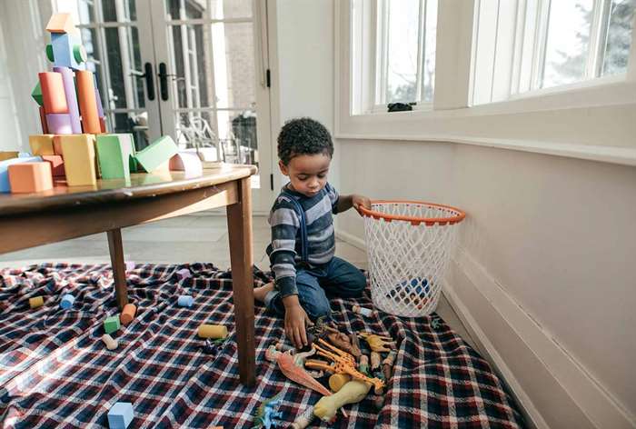 Toddler putting toys in basket.