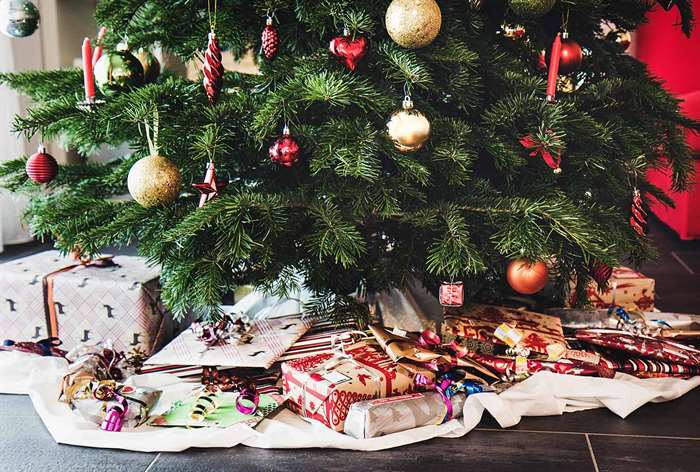 Christmas tree with presents on white paper skirt.