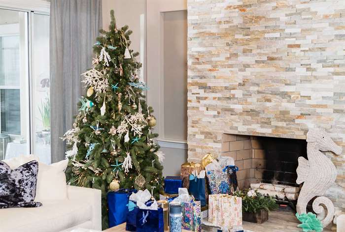 Christmas tree next to fireplace decorated with shells.