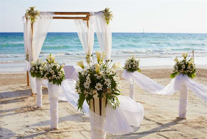 Wedding aisle on a beach, lined with flowers and linen