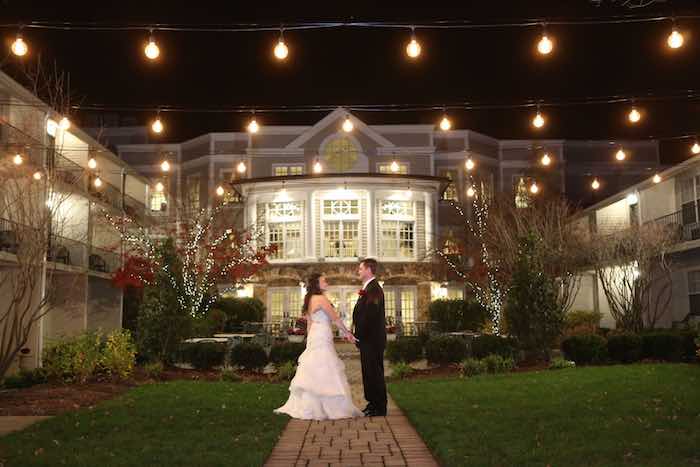 bride and groom under string lights