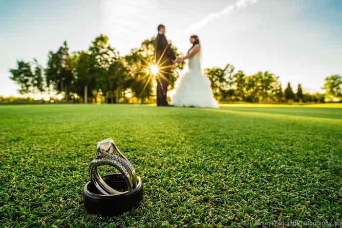 wedding rings with bride and groom in the background