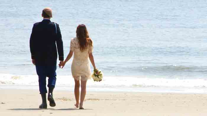 bride and groom walking on the beach