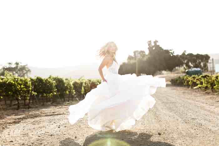 bride twirling in front of a vineyard