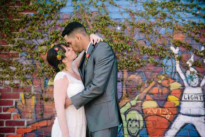 bride and groom kissing in front of street art