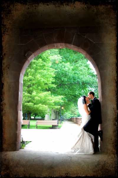 bride and groom kissing under an arch