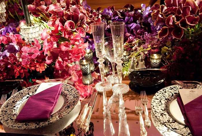 Table with purple orchid flower arrangements and napkins