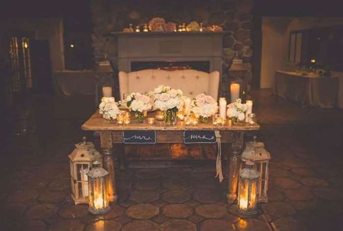 Rustic wood table with large lanterns and white and blush florals 